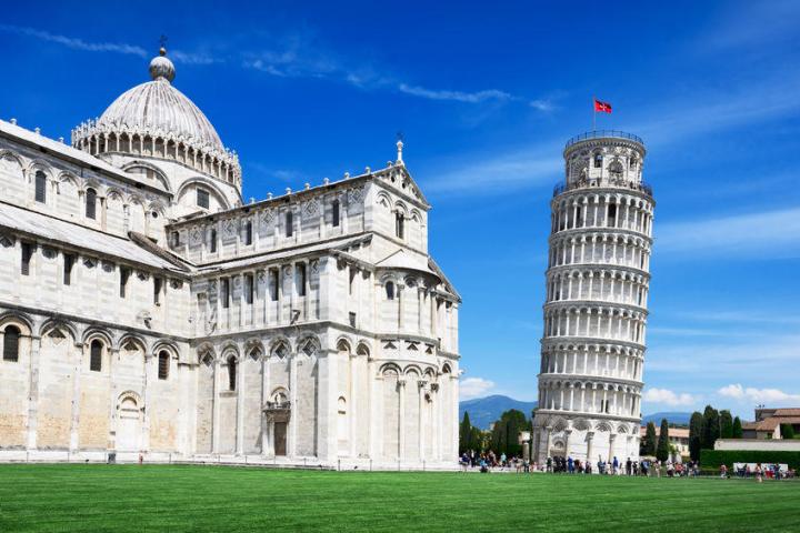 a large clock tower in front of Leaning Tower of Pisa