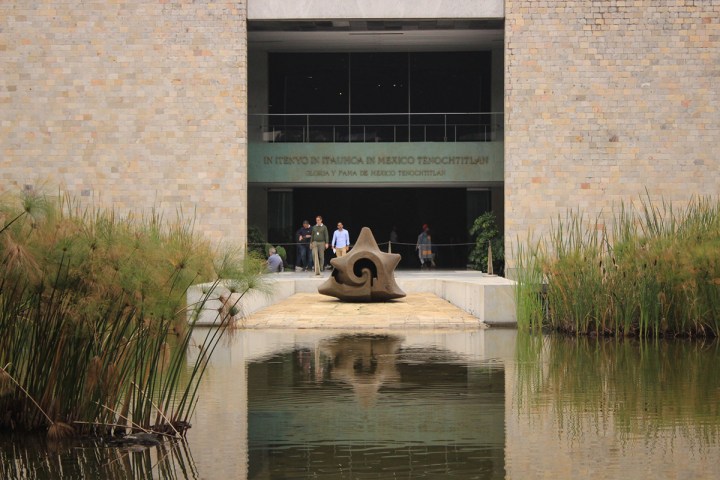 a bridge over water in front of a brick building