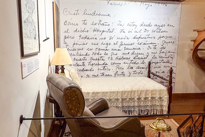 Cozy room with a reclined chair, bed, lamp, and handwritten text on the wall.