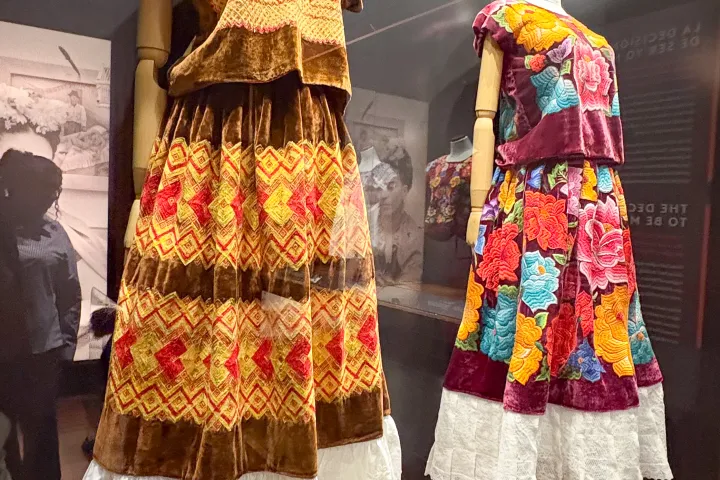 Two mannequins displaying colorful traditional Mexican dresses with embroidered designs.