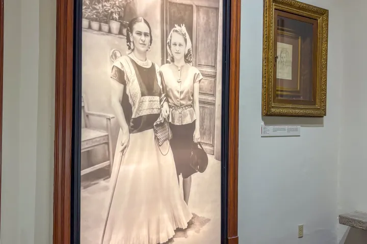 Black and white photo of two women in period clothing in a museum setting.