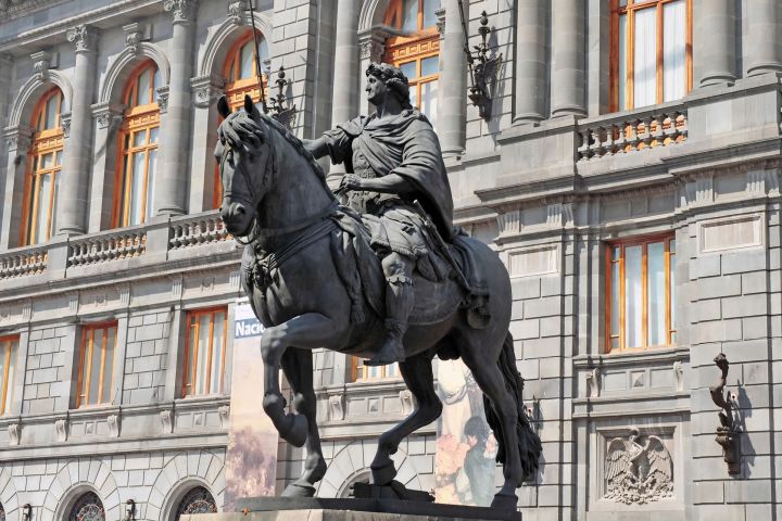a statue of a person riding a horse in front of a building