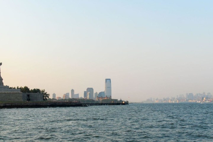 a large ship in a body of water with a city in the background
