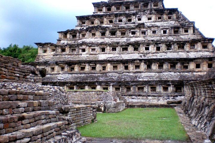 a large stone building with El Tajín in the background
