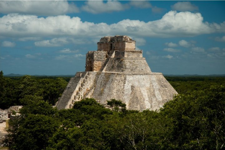 a castle on a cloudy day with Uxmal in the background