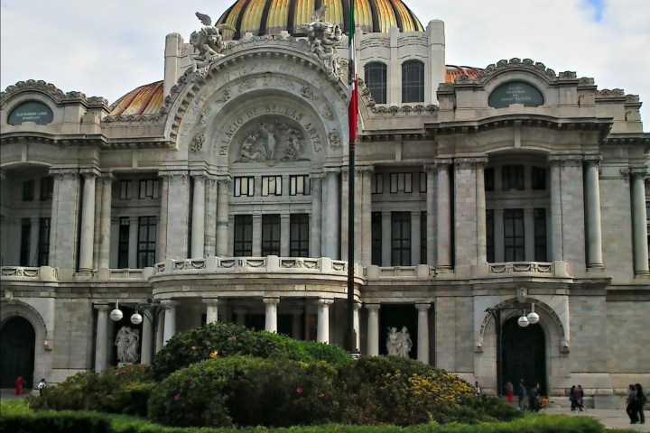 a large building with a grassy field with Palacio de Bellas Artes in the background