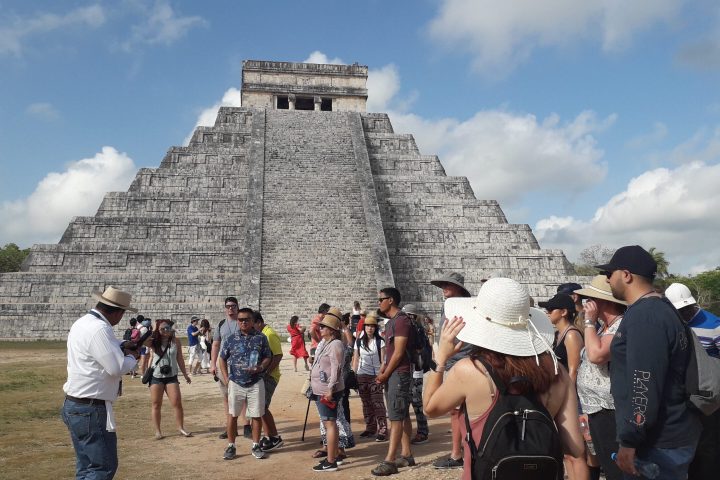 a group of people standing in front of Chichen Itza