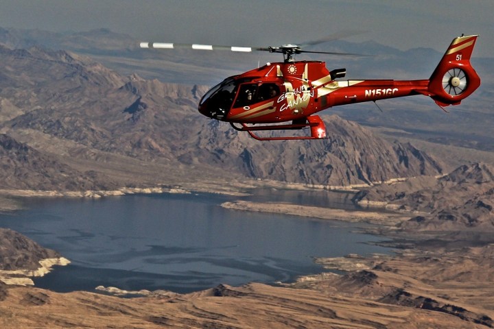 a plane flying over a body of water with a mountain in the background