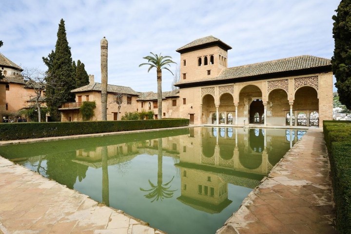 a large stone building with a clock on the side of a river