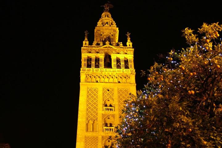 a clock tower lit up at night with Giralda in the background