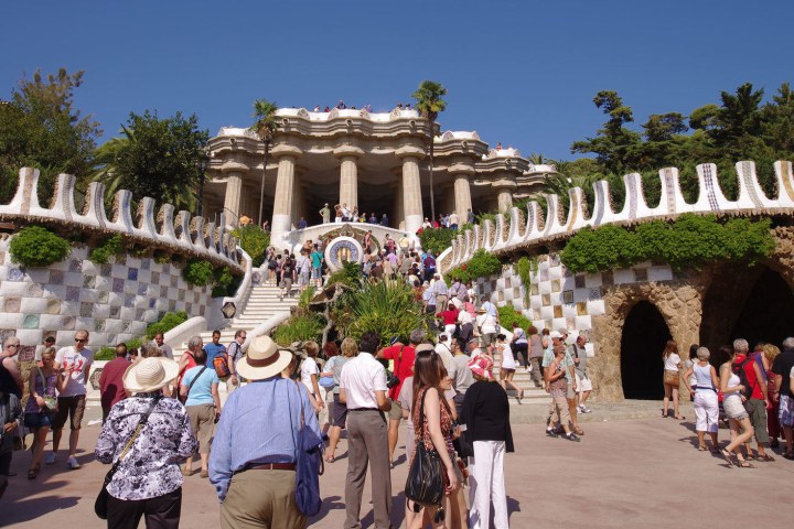 a group of people walking in front of a crowd with Park Güell in the background