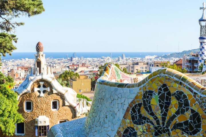 a group of tall buildings with Park Güell in the background