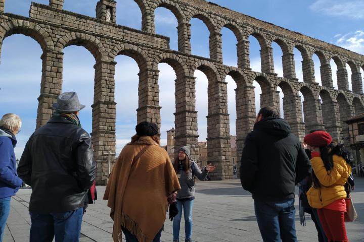a group of people standing in front of Aqueduct of Segovia