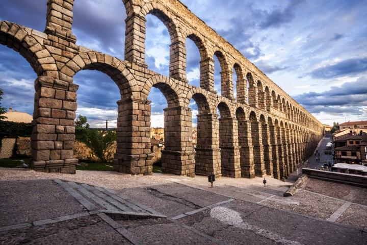 a stone building that has Aqueduct of Segovia in the background