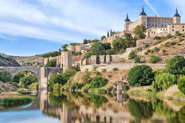 a castle on a bridge over a body of water surrounded by trees