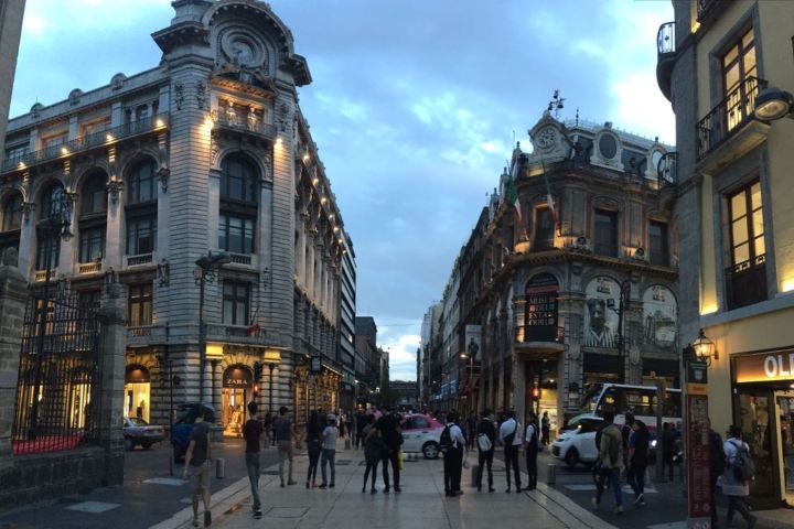a group of people walking down a street next to a clock tower