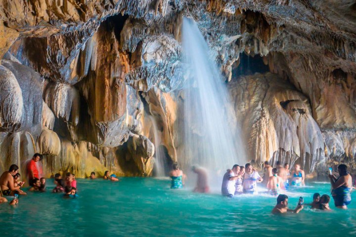 a group of people standing next to a waterfall