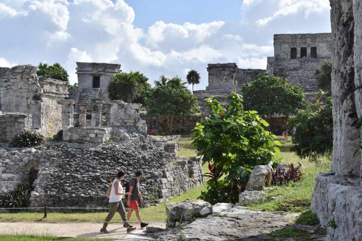 a group of people walking in front of a stone building