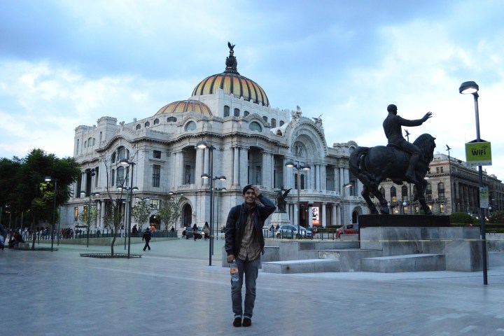 a statue of a man standing in front of Palacio de Bellas Artes