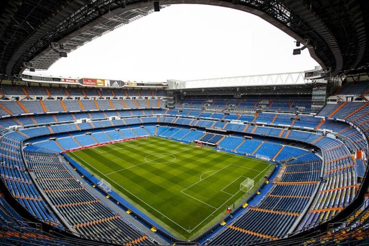 a stadium with a train on a steel track with Santiago Bernabéu Stadium in the background