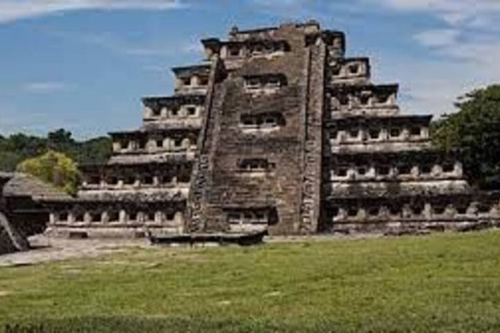 a castle on top of a grass covered field with El Tajín in the background