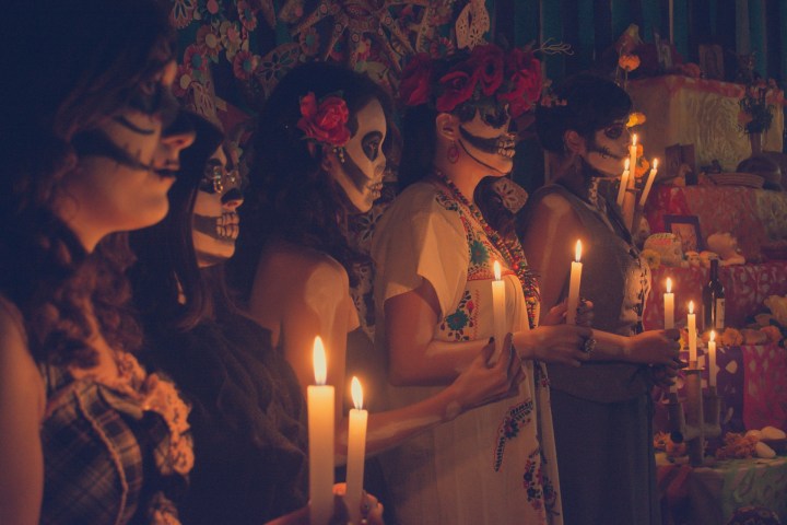 a group of people looking at a birthday cake with lit candles