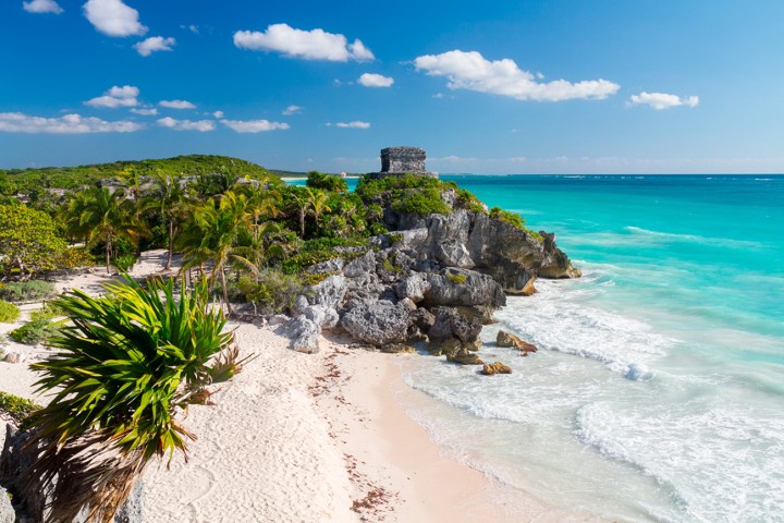 water next to the ocean with Tulum in the background