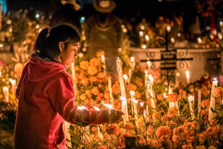 a person standing in front of a cake with lit candles