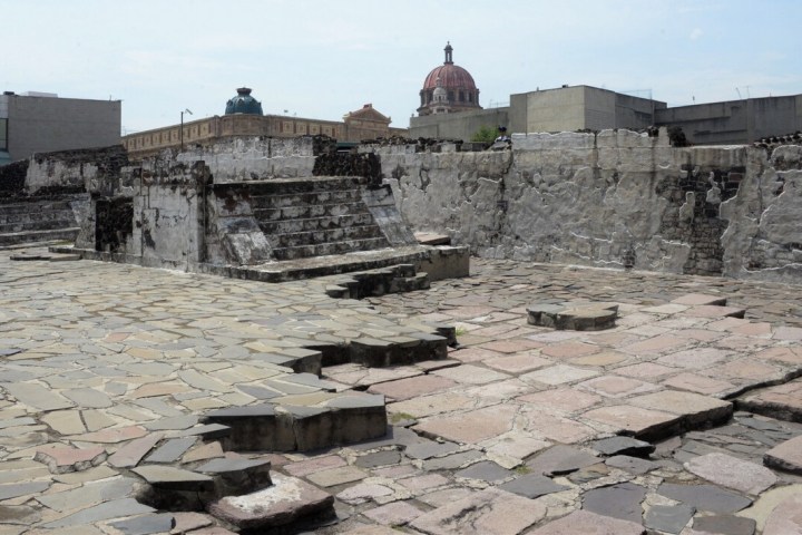 a stone building that has a bench in front of a brick wall