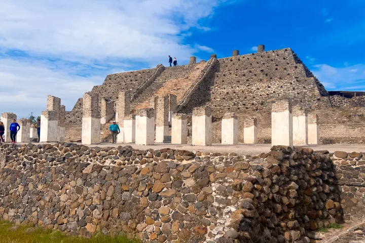 a large stone building with a flock of sheep in a rocky area