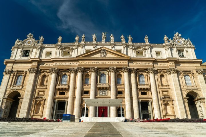 a large stone building with St. Peter's Basilica in the background