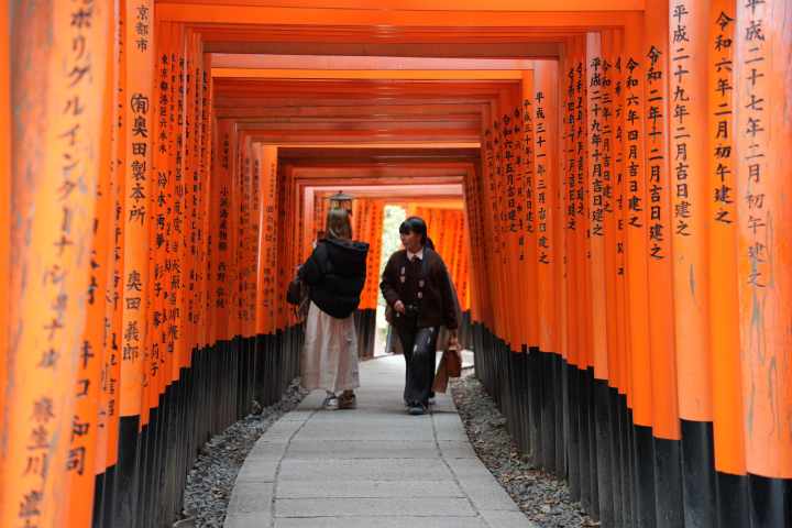 a person standing in front of a curtain with Fushimi Inari-taisha in the background