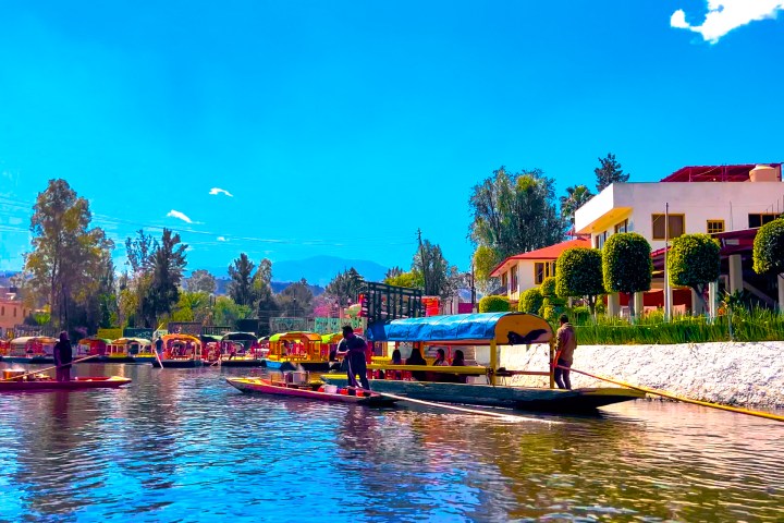 a small boat in a body of water with Xochimilco in the background