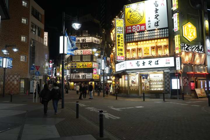 a group of people walking down the street in front of a store