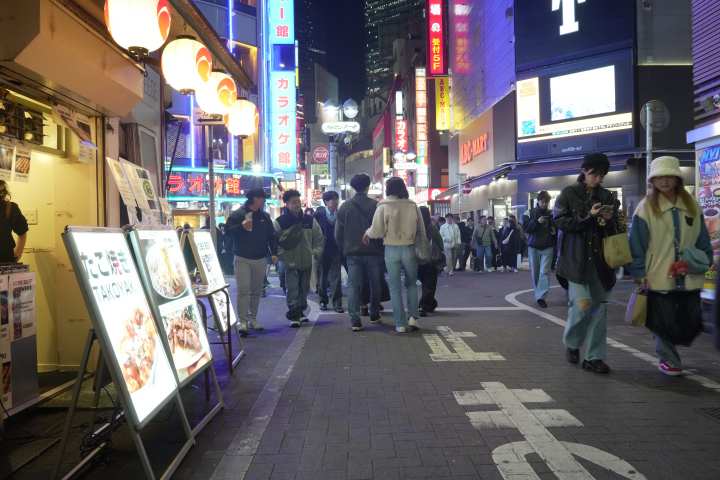 a group of people walking down the street in front of a store
