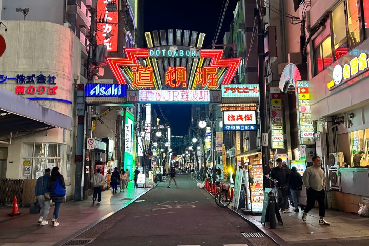 a group of people walking down the street in front of a store
