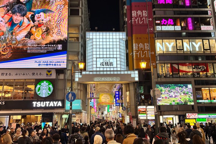a group of people walking down the street in front of a store