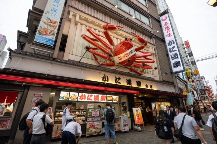 a group of people walking down a street in front of a store