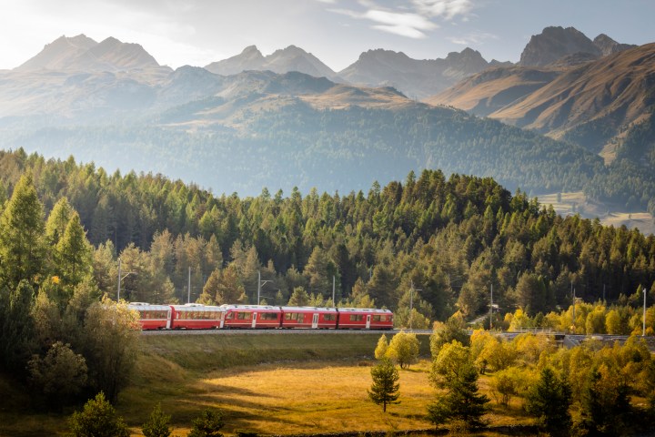 a large long train on a track with a mountain in the background