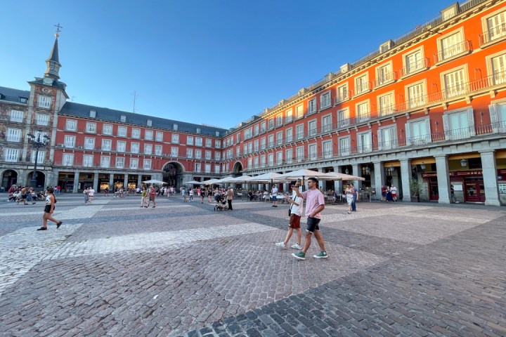 a group of people walking in front of Plaza Mayor, Madrid